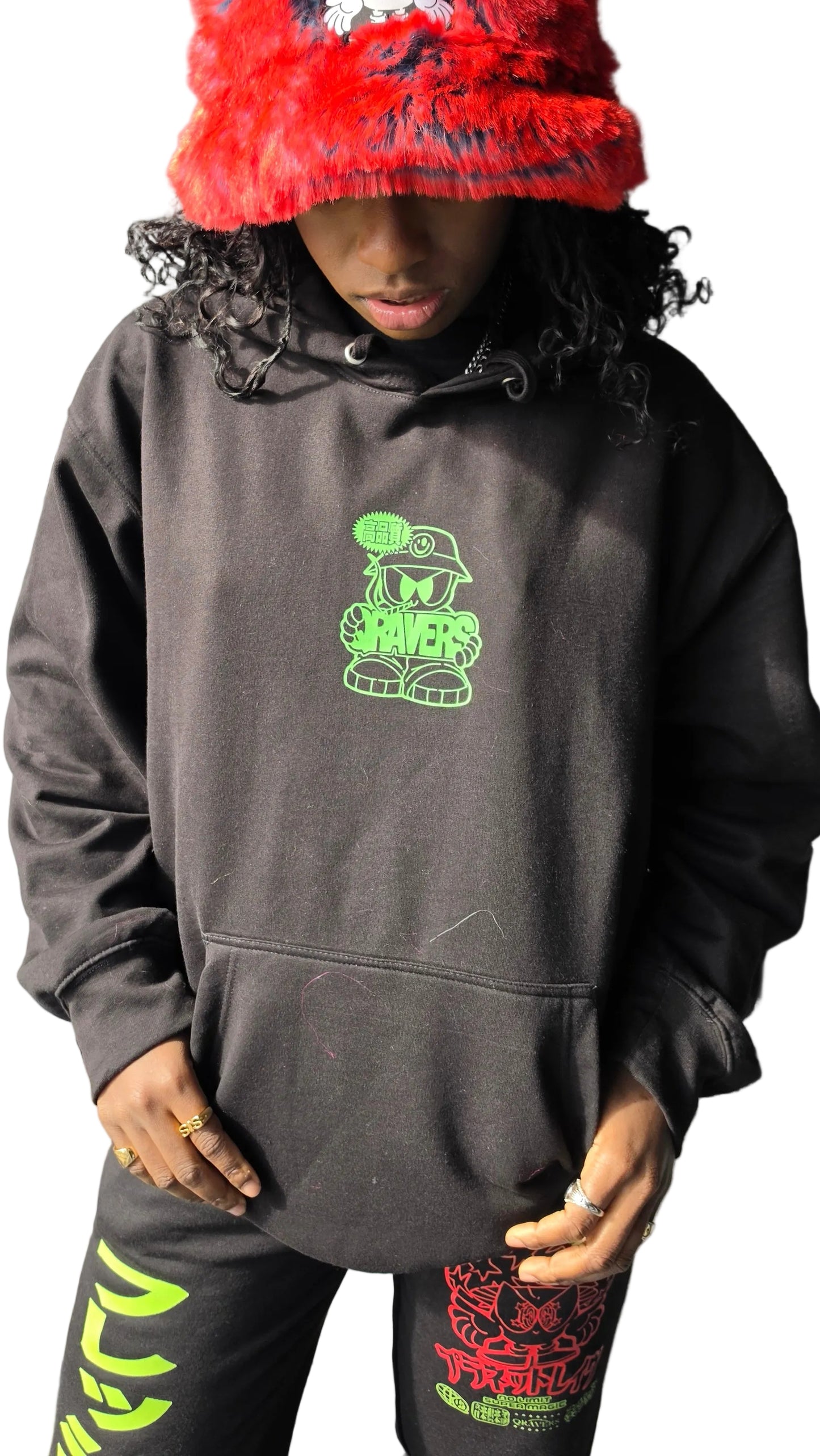 Person wearing a dark hoodie with green graphics and a red hat.
